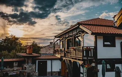 a house with a balcony with a sunset in the background at Seven Springs Hotel in Banya