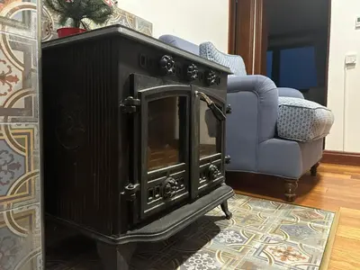 a black fireplace in a living room with a chair at Stoykite-Pamporovo Nature Retreat in Stoykite