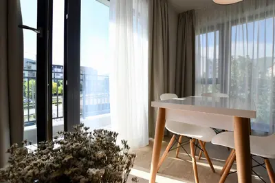 a room with a table and chairs and a large window at Connect Living Apartments in Sofia