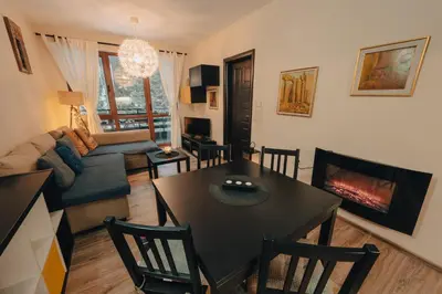 a living room with a table and a fireplace at Max Holiday Apartment in Pamporovo