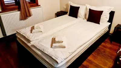 a large bed with white sheets and pillows at ПАУНОВАТА КЪЩА in Yasă-Koriya