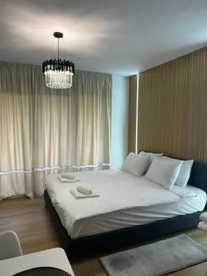 a bedroom with a large bed with a chandelier at Sandanski Apartments Park Center in Sandanski
