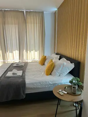 a bedroom with a bed with yellow pillows and a table at Sandanski Apartments Park Center in Sandanski