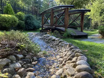 a bridge over a stream with a rock wall at Luxury Villa Borina in Zheleznitsa