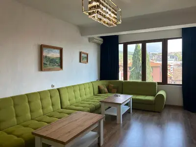 a living room with a green couch and a table at Didi Park House къща с две спални in Sandanski