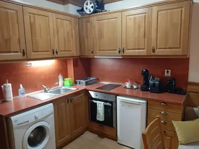 a kitchen with wooden cabinets and a sink and a dishwasher at Private Studio Pirin Golf Hotel Bansko in Razlog
