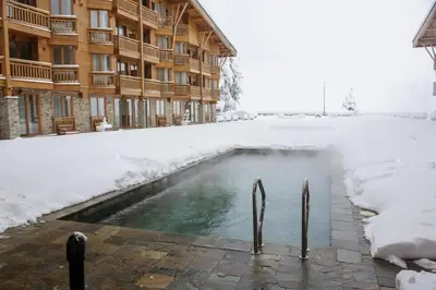 a swimming pool in the snow in front of a building at Private Studio Pirin Golf Hotel Bansko in Razlog