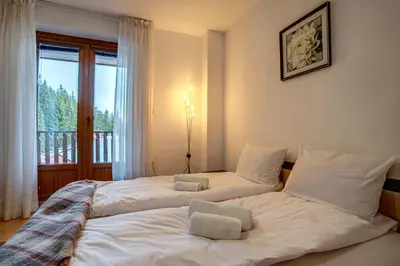two beds in a room with a window at MyPlace Pamporovo апартаменти за отдих in Pamporovo