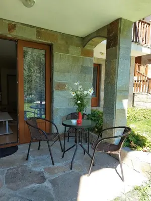 a patio with two chairs and a table with a vase of flowers at MyPlace Pamporovo апартаменти за отдих in Pamporovo