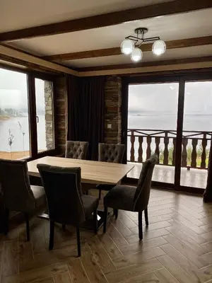 a dining room with a table and chairs and windows at Къщи за гости 