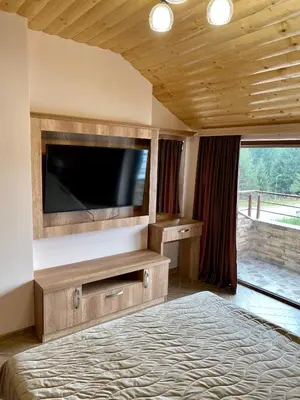 a bedroom with a flat screen tv and a bed at Къщи за гости 