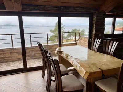 a dining room with a table and chairs and a large window at Къщи за гости 