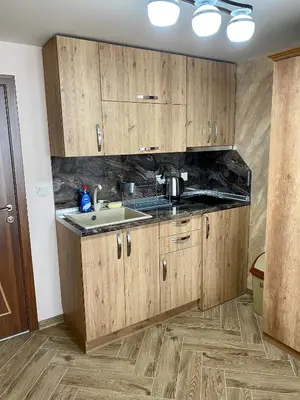 a kitchen with wooden cabinets and a sink at Къщи за гости 