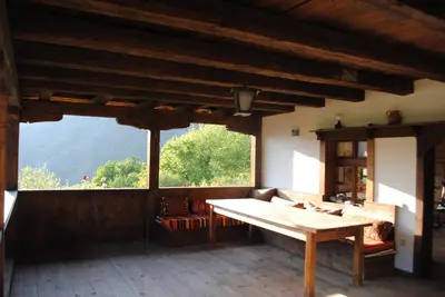 a living room with a table and a large window at Къща за гости Кануш войвода in Kovachevitsa