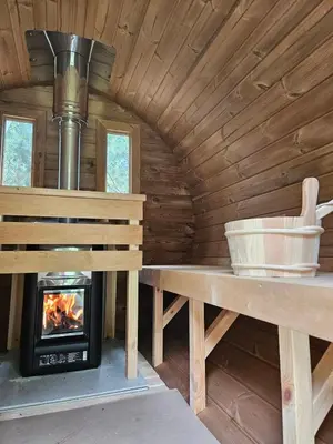a fireplace in a log cabin with a bench and a stove at Zarevo Glamping in Skobelevo