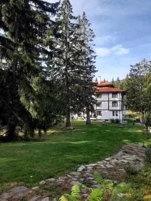 a large building with trees in front of a yard at Луксозен апартамент - 