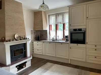 a kitchen with white cabinets and a fireplace at Willy Villy`s house in Chepelare