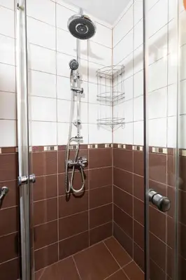 a shower in a bathroom with brown tiles at 1BD apartment in a calm area near the centre by Flat Mаnager in Plovdiv