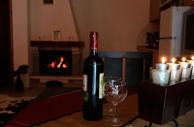 a bottle of wine and a glass on a table with a fireplace at 2 bedroom, 2 showeroom Villa suitable for a family skication and remote working in Pamporovo
