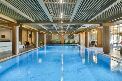 a large swimming pool with blue water in a building at Pirin Golf Studio Apartment in Razlog