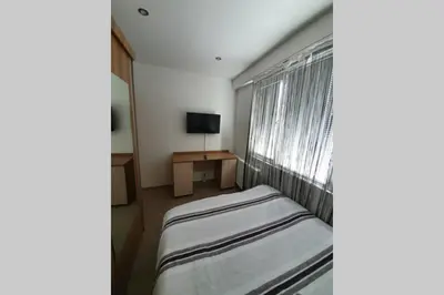 a bedroom with a bed and a window with a television at Луксозен апартамент с WiFi на 10км от Боровец in Samokov
