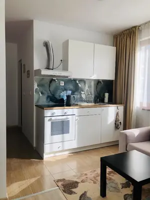a kitchen with white cabinets and a table in a room at Temerso Studio-Apartment in Bansko