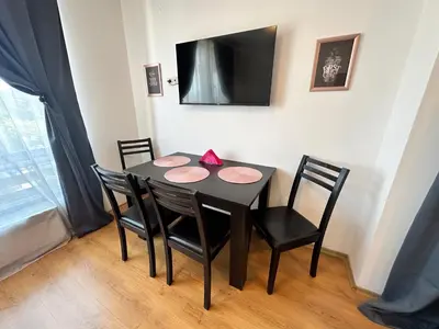 a black dining room table with four chairs and a television at Aspen Golf - private apartments in Razlog