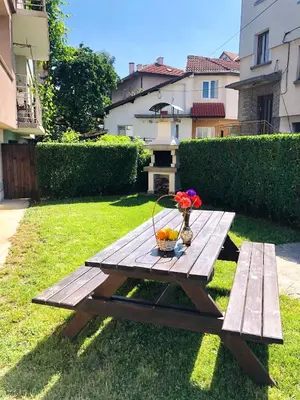 a picnic table with a bowl of flowers and a basket of fruit at Pavlovi Apartments in Samokov