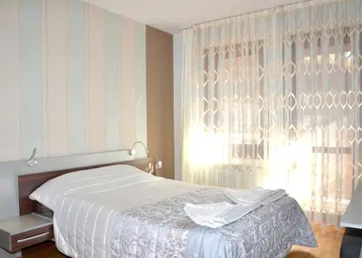 a bedroom with a white bed and a window at Къщи за гости 