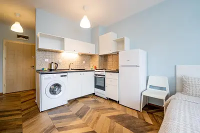 a kitchen with white cabinets and a washer and dryer at Cozy little apartment in Studentski grad in Sofia