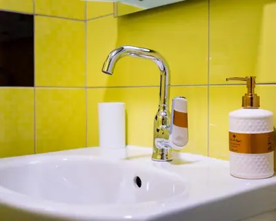 a bathroom sink with a faucet and toiletries on it at Cozy little apartment in Studentski grad in Sofia