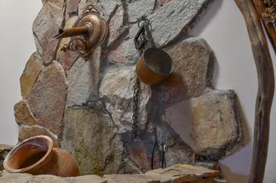 a stone wall with a copper pot and a hook at Villa Anna Luxury Lake Residence in Shtarkelovo Gnezdo