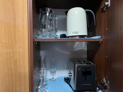 a cabinet with a stove and glasses on a table at Marina Apartment in Bansko