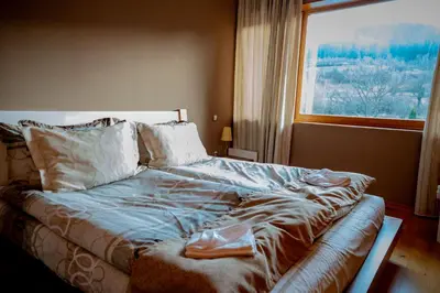 a bed in a bedroom with a large window at Luxury houses in Dobrinishte in Dobrinishte