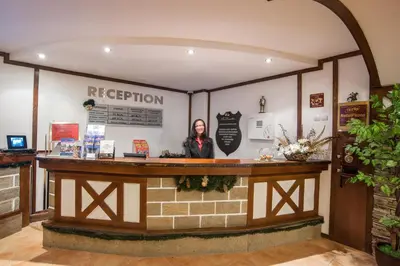 a woman standing at a reception counter in a building at Studio - Apartments Castle Complex 2 in Pamporovo