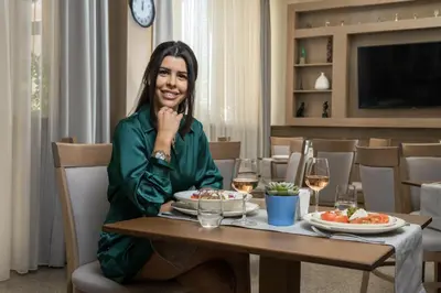 a woman sitting at a table with a plate of food at AquaSun Family Hotel in Sandanski
