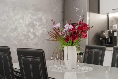 a vase of flowers on a table with chairs at City Apartments - a brand new luxury & comfy 2 in Asenovgrad