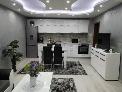 a kitchen with white cabinets and a table with chairs at City Apartments - a brand new luxury & comfy 2 in Asenovgrad