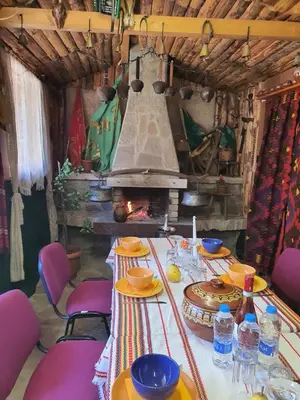 a table with chairs and a fireplace in a room at GUEST HOUSE TONI СТАИ за ГОСТИ ТОНИ in Ribarica