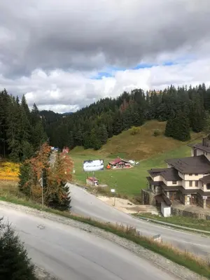 a view of a house on a hill next to a road at Апартамент Пампорово Палас - Pamporovo Palace in Pamporovo