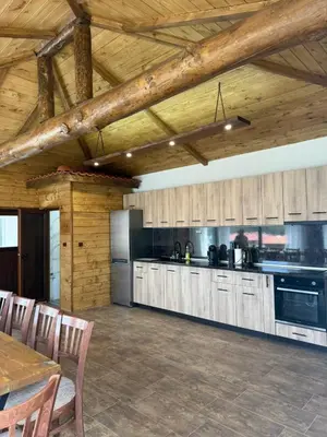 a large kitchen with wooden cabinets and a table at Вила Слънчев Бряг in Dospat