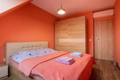 a bedroom with orange walls and a bed with towels on it at Apartment City View 2 in Sofia