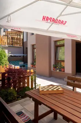 a picnic table under a white umbrella on a patio at Къща за гости