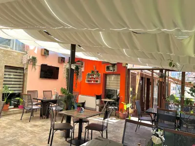 a patio with tables and chairs under a tent at Хотел Дива in Blagoevgrad