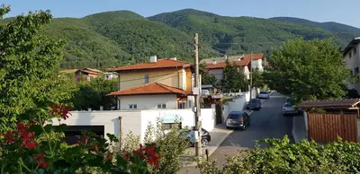 a street in a small town with mountains in the background at Апартаменти Гювийски in Sapareva Banya
