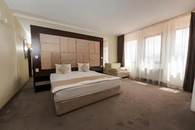 a bedroom with a large bed and a chair at Family Hotel The View & SPA in Tsigov Chark