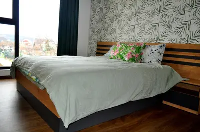 a bed with a wooden headboard and pillows on it at New Apartment at a Great Location in Blagoevgrad