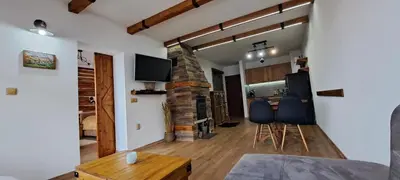 a living room with chairs and a stone fireplace at апартамент Гигови in Bansko
