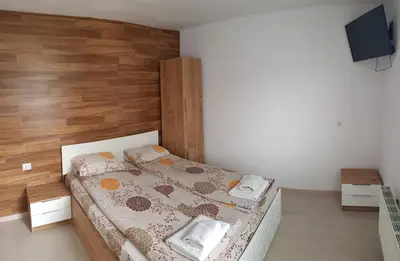 a bedroom with a bed with a wooden wall at Семеен Хотел-