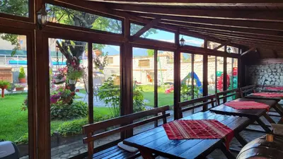 a porch with wooden tables and a view of a yard at Семеен Хотел-